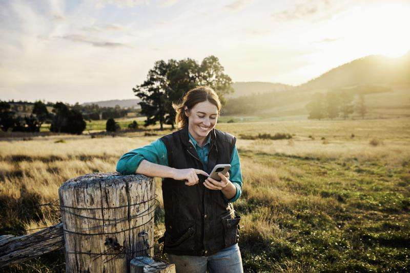 Young female farmer staying in touch via mobile technology from her farm in rural Tasmania, Australia.