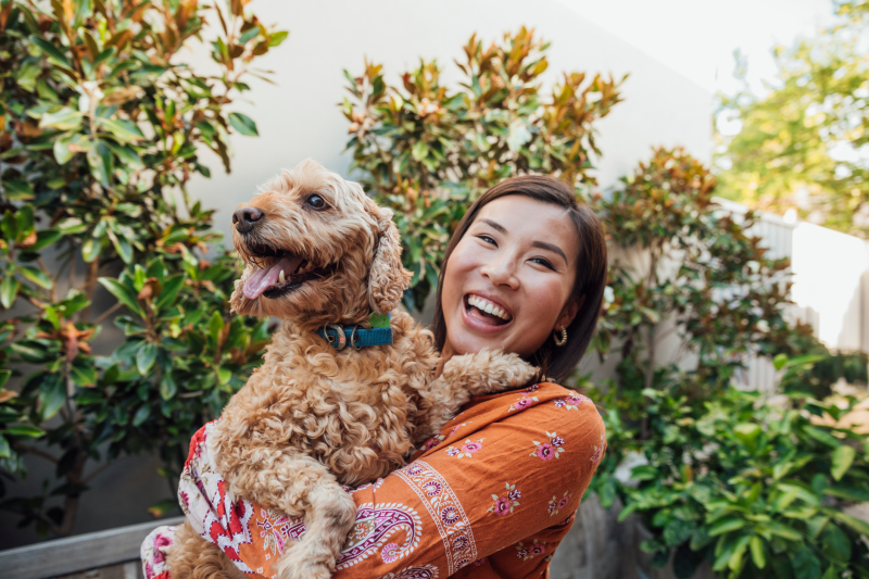 Woman in an orange top holding a brown puppy.